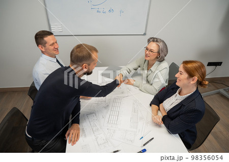 Business partners shake hands. Four business people are negotiating in the conference room. Business partners shake hands. Four business people are negotiating in the conference room. 98356054