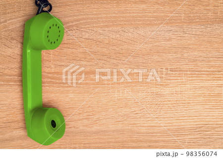 Old green telephone receiver hanging on the wooden background 98356074