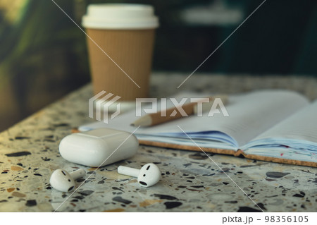 Take away coffee in craft recycling paper cup with paper notebook with wireless headphones. Mockup Coffee break. Audio healing, sound therapy wellness rituals, positive mental health habits listening Take away coffee in craft recycling paper cup with paper notebook with wireless headphones. Mockup Coffee break. Audio healing, sound therapy wellness rituals, positive mental health habits listening 98356105