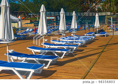 View of the pier with blue sun loungers and white umbrellas on the seashore in Kemer. Turkey 98356803