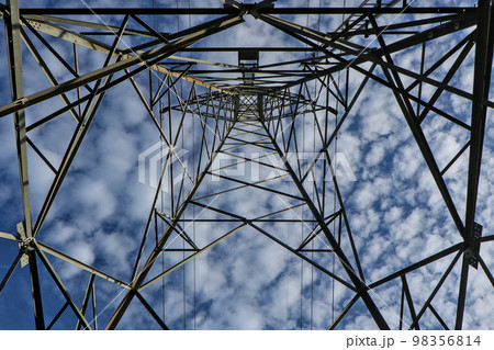 high voltage pole Taken from a low angle to the top of a tall pillar overlooking the sky and white clouds. high voltage pole Taken from a low angle to the top of a tall pillar overlooking the sky and white clouds. 98356814