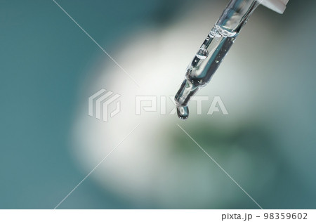 Closeup of face serum in transparent glass pipette. Natural oil, gel, cleaner. Anti age cosmetics and healthcare concept in macro. Dose of retinol. Virus research. Web banner for design Closeup of face serum in transparent glass pipette. Natural oil, gel, cleaner. Anti age cosmetics and healthcare concept in macro. Dose of retinol. Virus research. Web banner for design 98359602