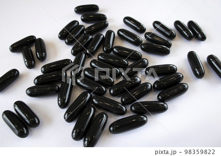 Black Activated Charcoal in capsules on a white background, top view. Treatment of the digestive system and poisoning 98359822