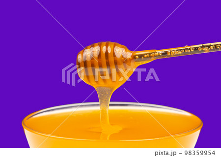 fresh fragrant honey drips from a spoon into a plate on a colored background. fresh fragrant honey drips from a spoon into a plate on a colored background. 98359954