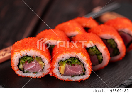 California sushi roll with tuna, avocado cucumber and tobiko caviar served on black board close-up - Japanese food California sushi roll with tuna, avocado cucumber and tobiko caviar served on black board close-up - Japanese food 98360489