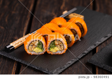 California sushi roll with eel, cucumber and tobiko caviar served on black board close-up - Japanese food 98360491