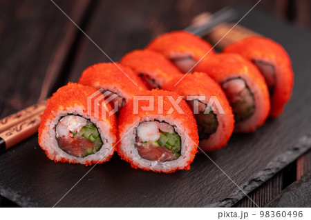California sushi roll with salmon crab, cucumber and tobiko caviar served on black board close-up - Japanese food 98360496
