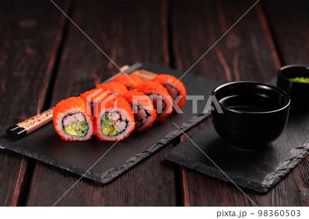 California sushi roll with crab, avocado, cucumber and tobiko caviar served on black board close-up - Japanese food California sushi roll with crab, avocado, cucumber and tobiko caviar served on black board close-up - Japanese food 98360503