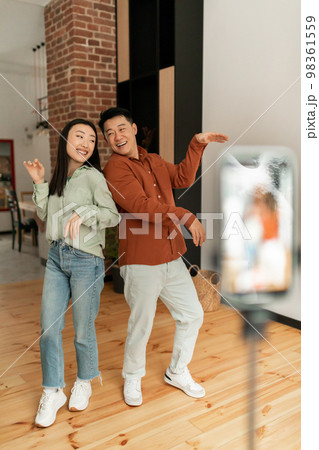 Asian couple influencers recording video on smartphone, dancing on camera, lifestyle vloggers making content for blog 98361559