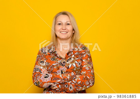 Pretty caucasian blonde woman posing smiling with arms crossed isolated on orange studio background. Pretty caucasian blonde woman posing smiling with arms crossed isolated on orange studio background. 98361885