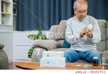Asian old man buy herbal self cure Rx pill online from pharmacy, worried senior man with medicine pills he read on see how to take pills before taking, home isolation, Medical service concept 98363453