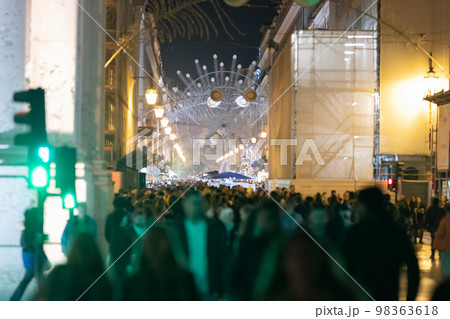 People crowd on a European street decorated for Christmas People crowd on a European street decorated for Christmas 98363618