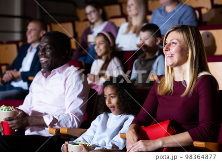 Laughing woman watching funny movie in cinema with family Laughing woman watching funny movie in cinema with family 98364877