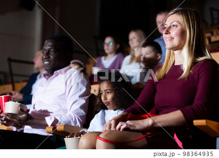 International family enjoys watching comedy in cinema hall International family enjoys watching comedy in cinema hall 98364935