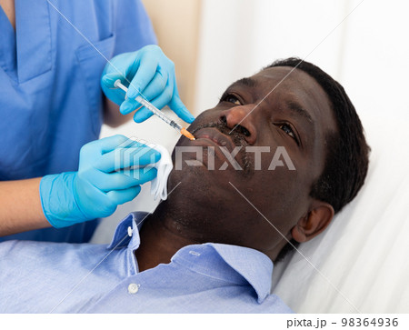 African male patient getting beauty injection 98364936