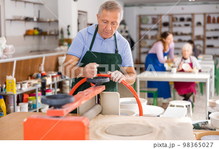 male potter works with machine clay press roller 98365027