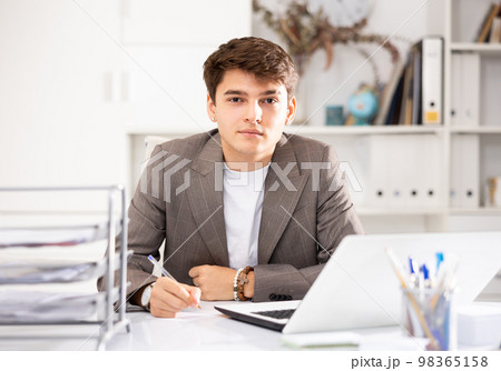 Male worker engaged in business activities at workplace in office 98365158