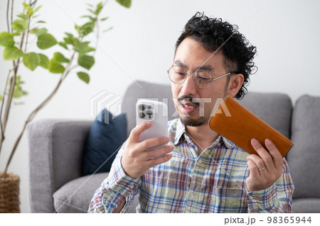 アプリに課金してスマホと財布を持つ男性 アプリに課金してスマホと財布を持つ男性 98365944