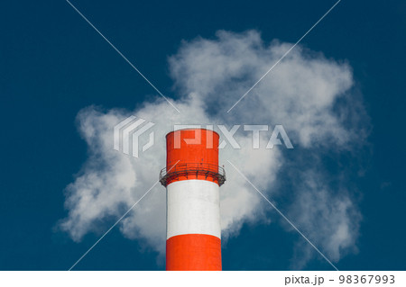 Pollution of the environment, ecology and air. Withdrawal of combustion products of soot, smoke and gases from the pipe of an industrial plant into the atmosphere against the background of a blue sky 98367993