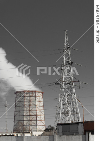 Smoke cooling tower pollution of the surrounding air gray sky environment of the atmosphere from the industrial plant and power lines high voltage tower 98367994