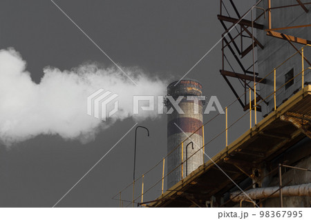 Pollution of the environment, ecology and air. Withdrawal of combustion products of soot, smoke and gases from the pipe of an industrial plant into the atmosphere against the background of a gray sky Pollution of the environment, ecology and air. Withdrawal of combustion products of soot, smoke and gases from the pipe of an industrial plant into the atmosphere against the background of a gray sky 98367995