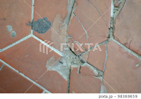 The road surface or walkway is made of broken and damaged orange bricks. 98369659