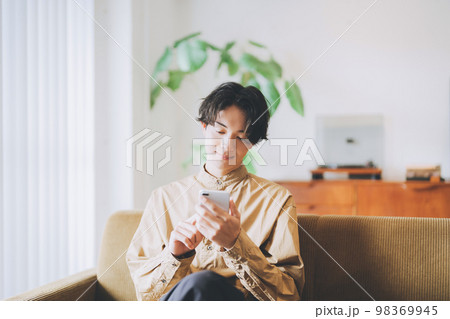 ソファに座ってスマホを見る男性 ソファに座ってスマホを見る男性 98369945