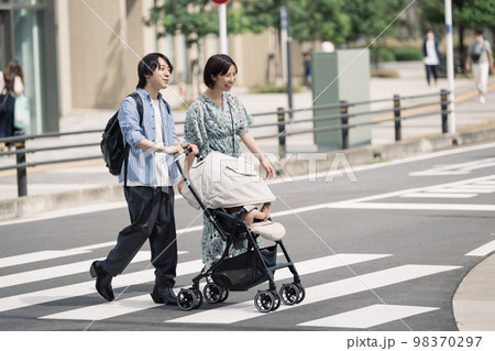 横断歩道を渡る育児中の夫婦 98370297