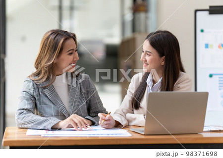 Working together on project. Two young asian business colleagues working on laptop computer. 98371698