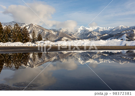 水鏡に映る雪の大源太山と上越国境の峰々 98372381