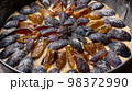 Macro caramelized in sugar syrup pieces of plums in round baking dish on wooden table 98372990