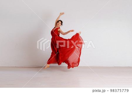Dancer in a red flying dress. Woman ballerina dancing on a white studio background 98375779