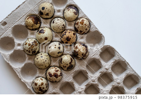 Spotted quail eggs in an egg box on a light background, natural eco-friendly products. 98375915