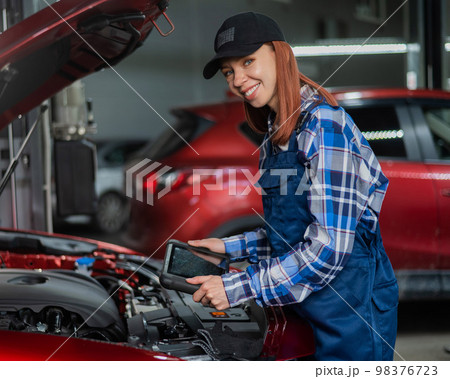 Caucasian female auto mechanic uses a special computer to diagnose faults.  98376723