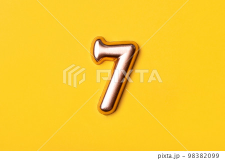 Metal number seven on a yellow background. Top view. 98382099