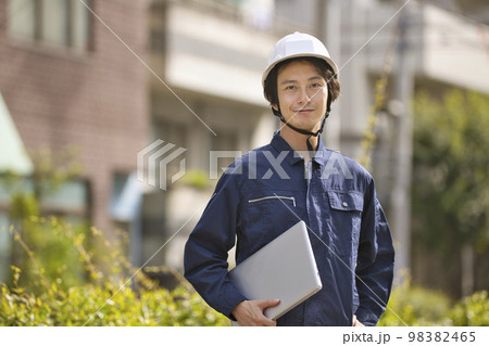 建設現場でパソコンを見る作業服の男性 98382465