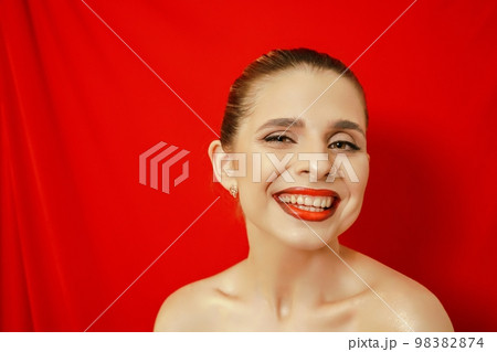 Portrait of a smiling beautiful young woman. Red background. Studio shot. 98382874
