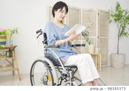 家で読書する車椅子に乗った障がい者女性 98383373