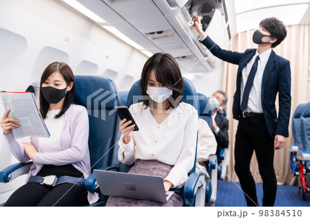 マスクをして飛行機に乗る乗客 98384510