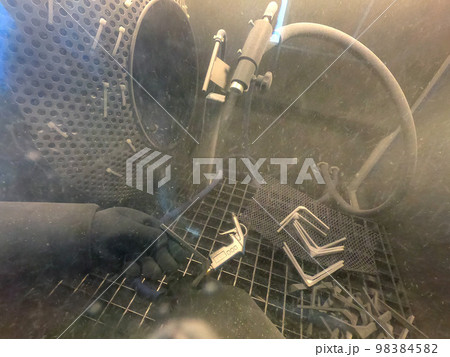 Shot blasting. Shot blasting of model printed on 3D printer from polyamide powder. A worker in sealed rubber gloves cleans the object by shot blasting in a shot blasting chamber. Industrial machine Shot blasting. Shot blasting of model printed on 3D printer from polyamide powder. A worker in sealed rubber gloves cleans the object by shot blasting in a shot blasting chamber. Industrial machine 98384582