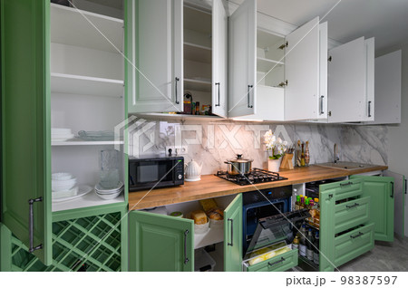 Doors open and drawers pulled out at new green and white kitchen furniture 98387597