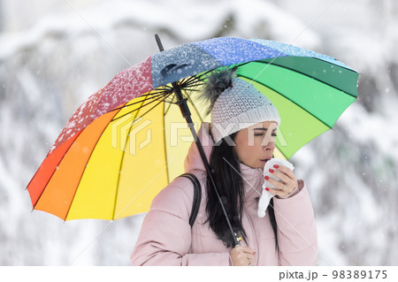 Woman holding umbrella on the cold rainy day coughs and covers her mouth Woman holding umbrella on the cold rainy day coughs and covers her mouth 98389175
