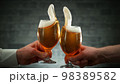 Two glasses of beer in cheers gesture, splashing. 98389582