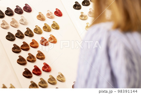 Hairdresser salon Woman chooses, looks at hair color samples on palette swatch book in stylist office or home. Beautician, dyeing or changing hair colour, natural, non-toxic, safe haircare concept 98391144