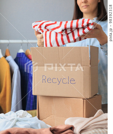 recycling, a woman collects clothes for donation and puts them in a cardboard box recycling, a woman collects clothes for donation and puts them in a cardboard box 98392318
