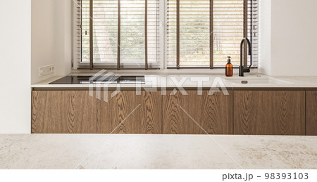 Interior of light kitchen with oak furniture, induction hob with integrated hood, white walls. Japandi interior concept 98393103