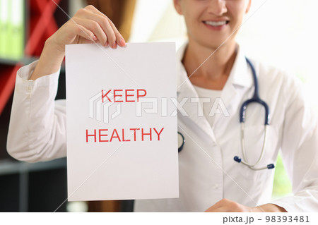Paper with words keep healthy close up and female doctor with stethoscope in background. 98393481