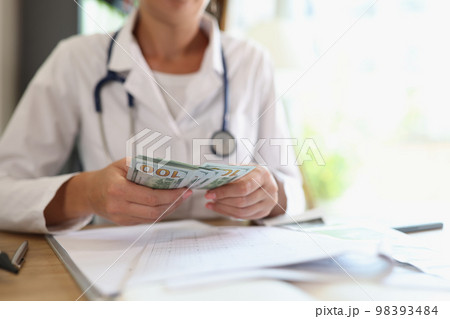 Doctor counts money in her hands in medical clinic. Doctor counts money in her hands in medical clinic. 98393484