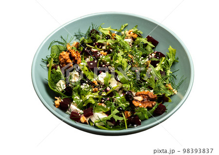Salad with beets rucola parsley herbs feta cheese walnuts in a bowl on isolated background. 98393837