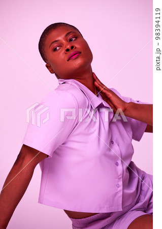 Overjoyed plus size millennial black woman in purple t-shirt and shorts sitting on floor relaxing isolated on purple studio background 98394119